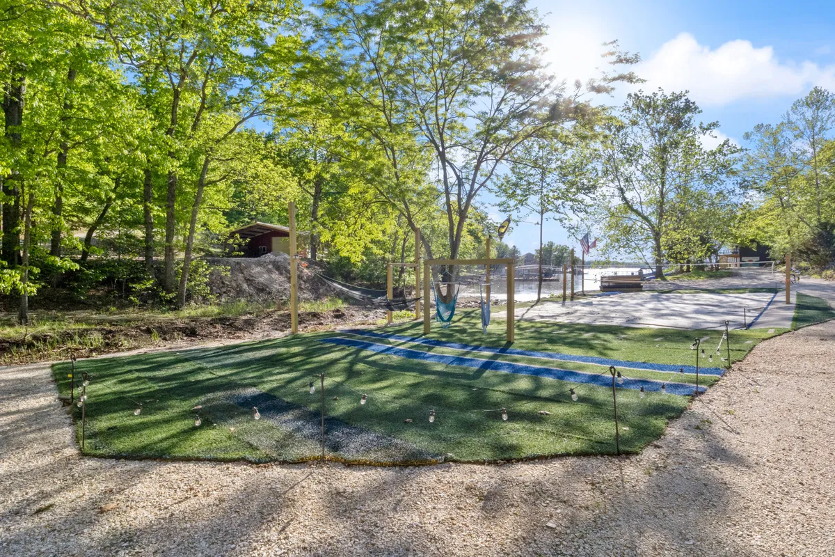 This exterior image showcases a swing set and hammock set among surrounding trees, with a play area and a beautiful water view visible in the background. The scene radiates a playful yet serene mood, perfect for family and pet activities.
