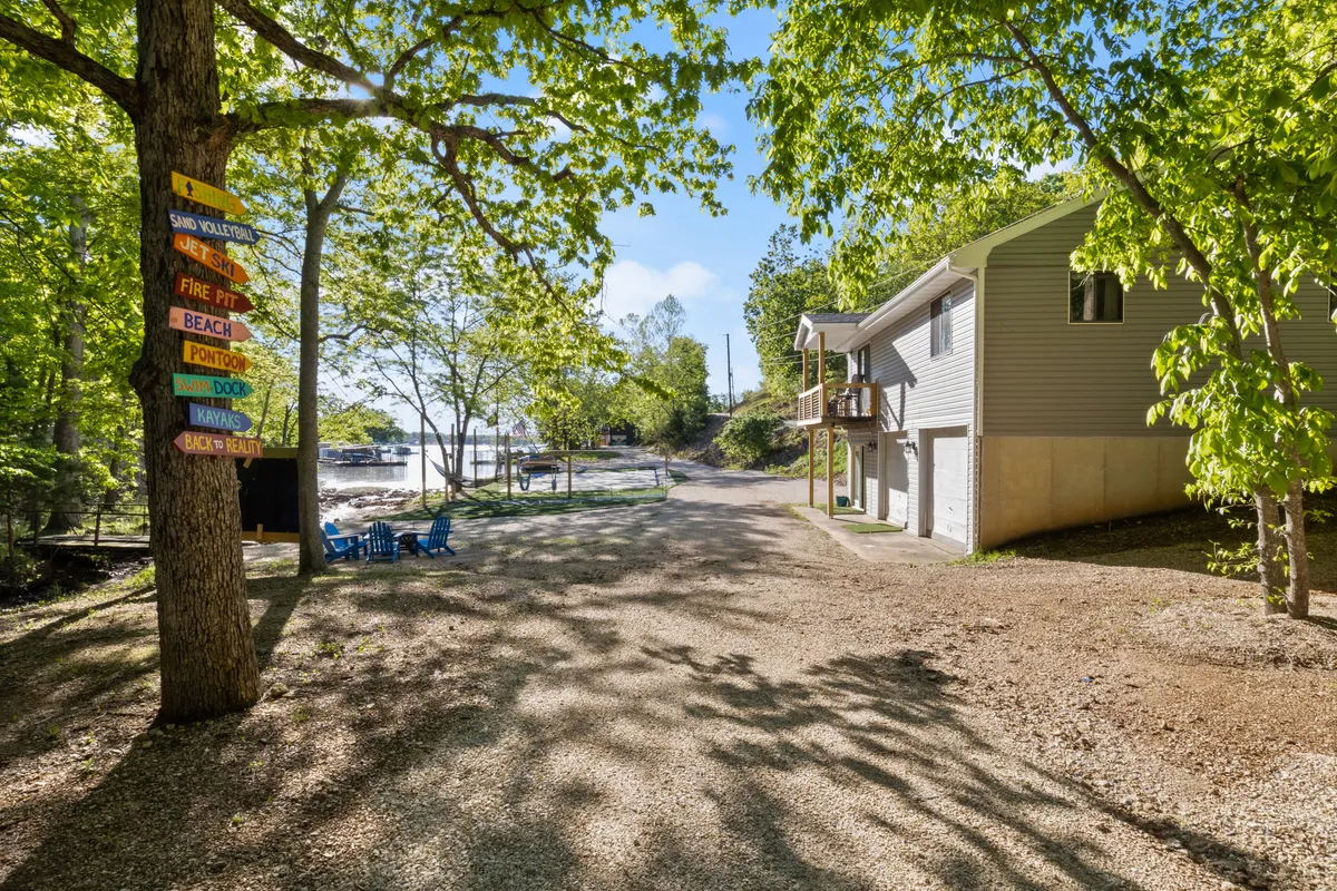 This image shows a signpost with directional signs, a pathway leading to the lake, and the exterior of the property. The scene is welcoming, featuring lush greenery and highlighting both the house and the easy access to the lake. The image evokes a sense of arrival and exploration, inviting guests to discover the area and the experiences awaiting them nearby.