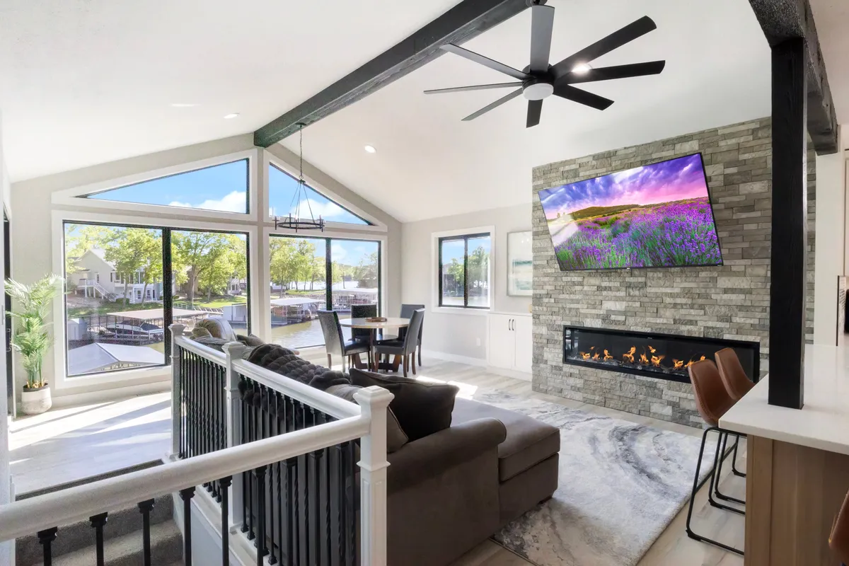An open-plan living and dining area with a spacious dining table, comfortable sofa, warm fireplace, and large windows that provide views of the sunset. The space feels cozy and ideal for gatherings, combining relaxation and dining in a single setting.