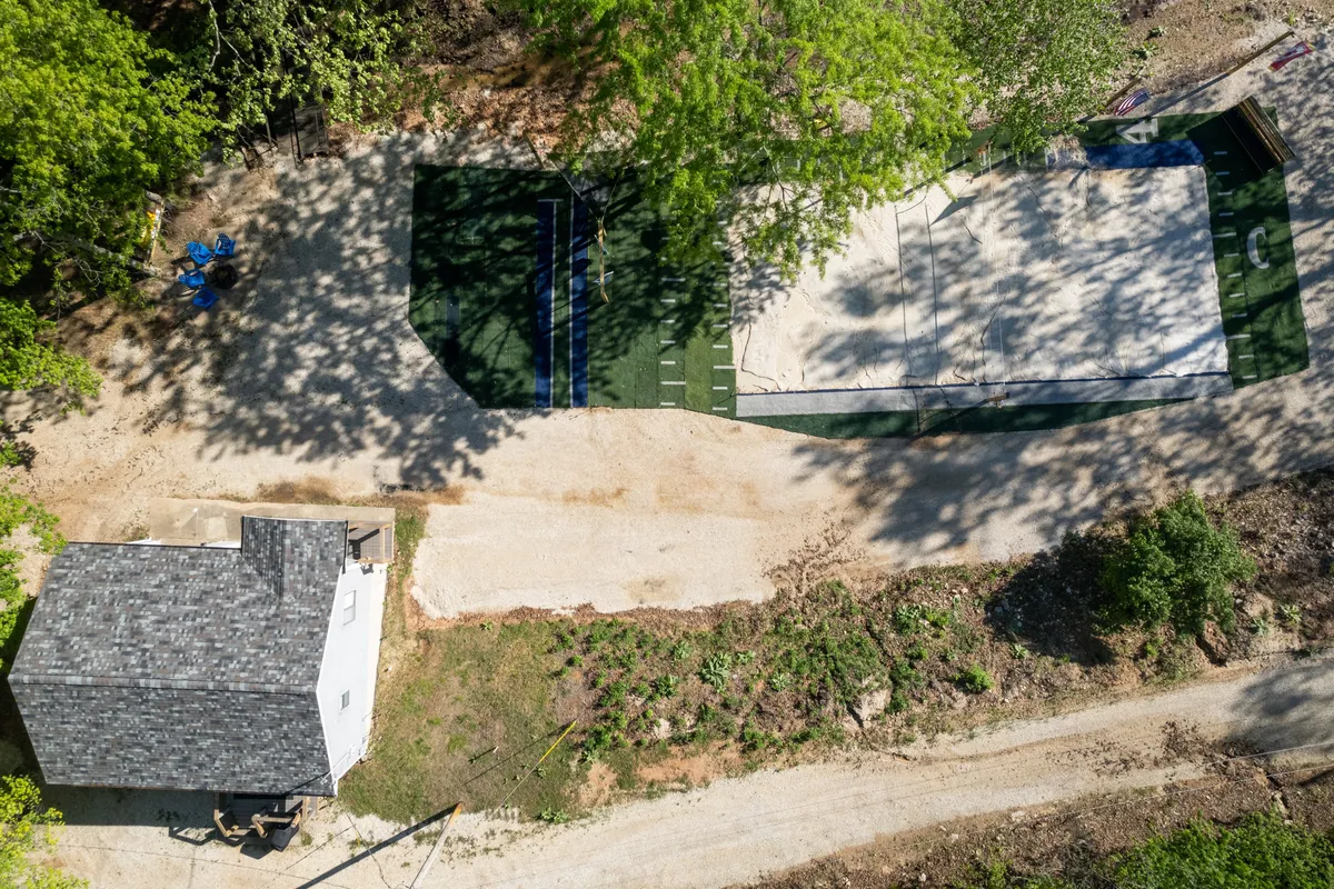 This exterior image features a small house adjacent to a sports court, surrounded by lush greenery. The scene is vibrant and playful, suggesting space for outdoor games, friendly competitions, and relaxed get-togethers. Families and groups can be imagined gathering here for barbecues or outdoor activities.