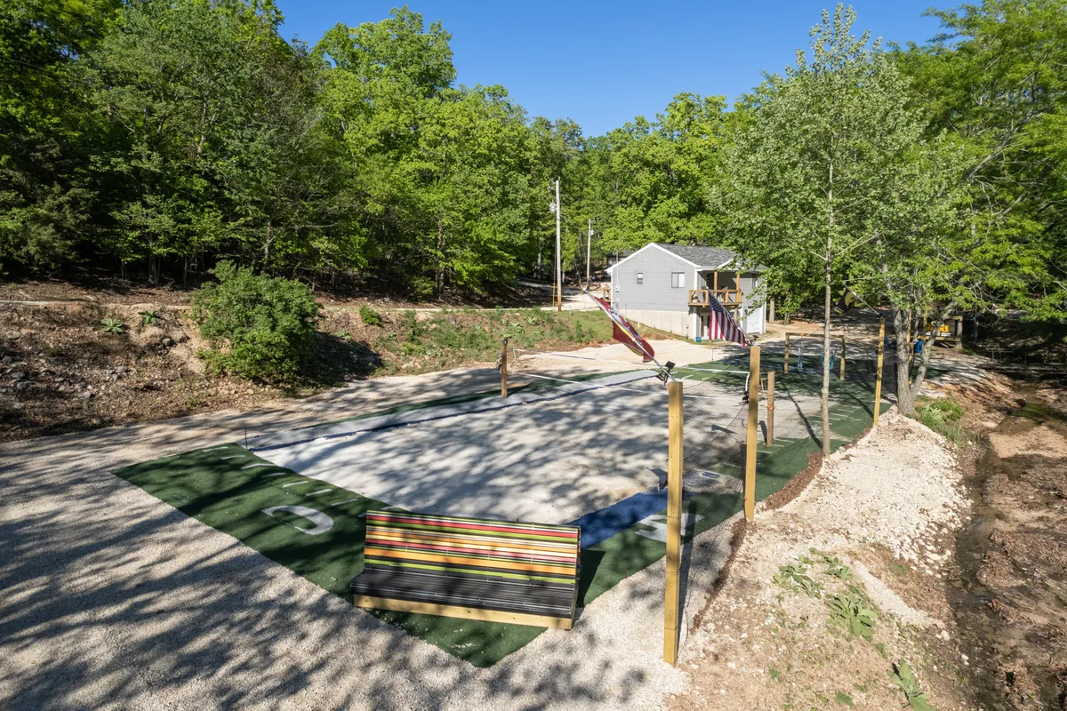 The photo highlights a cheerful playground area with a colorful bench, set against the backdrop of a house and green trees. The lively mood and facilities convey a place for children to play, while adults can relax nearby or participate in family gatherings and outdoor meals.
