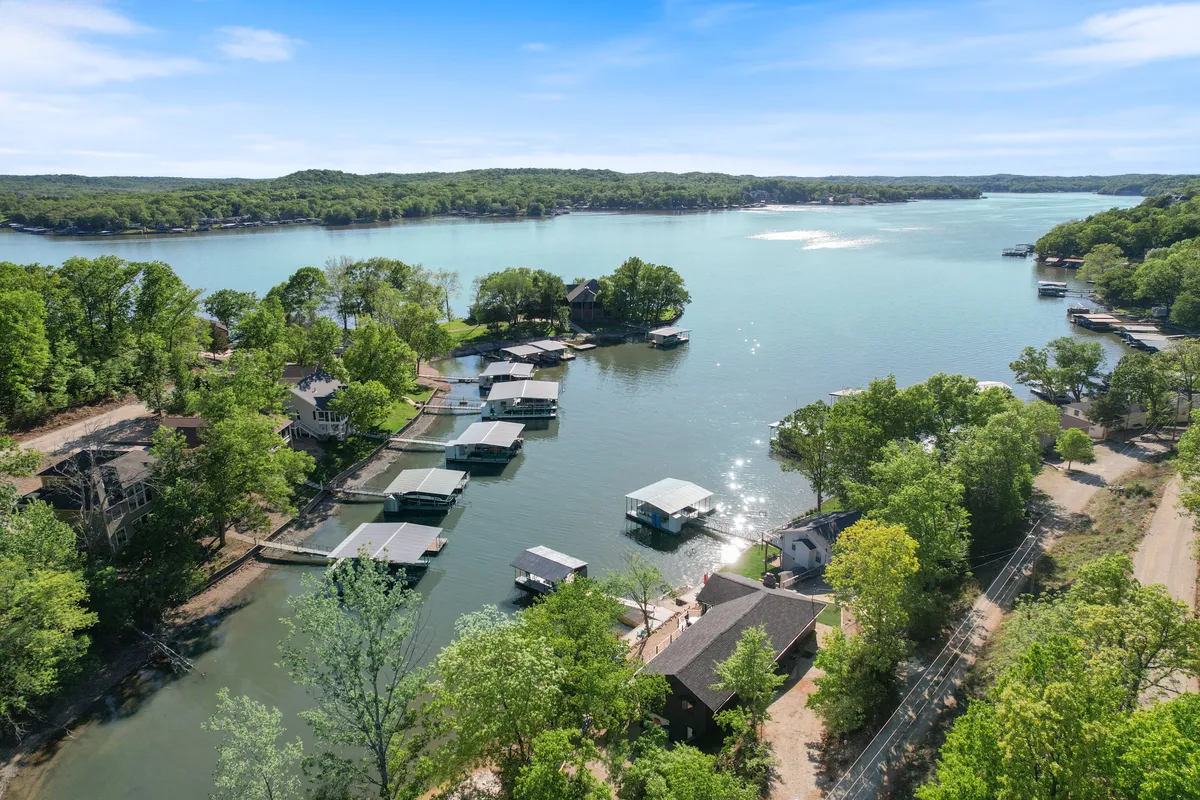 A panoramic view of the lake, dock, nearby houses, and surrounding trees. The image conveys a relaxing atmosphere perfect for water activities, fishing, and quiet moments by the shore.